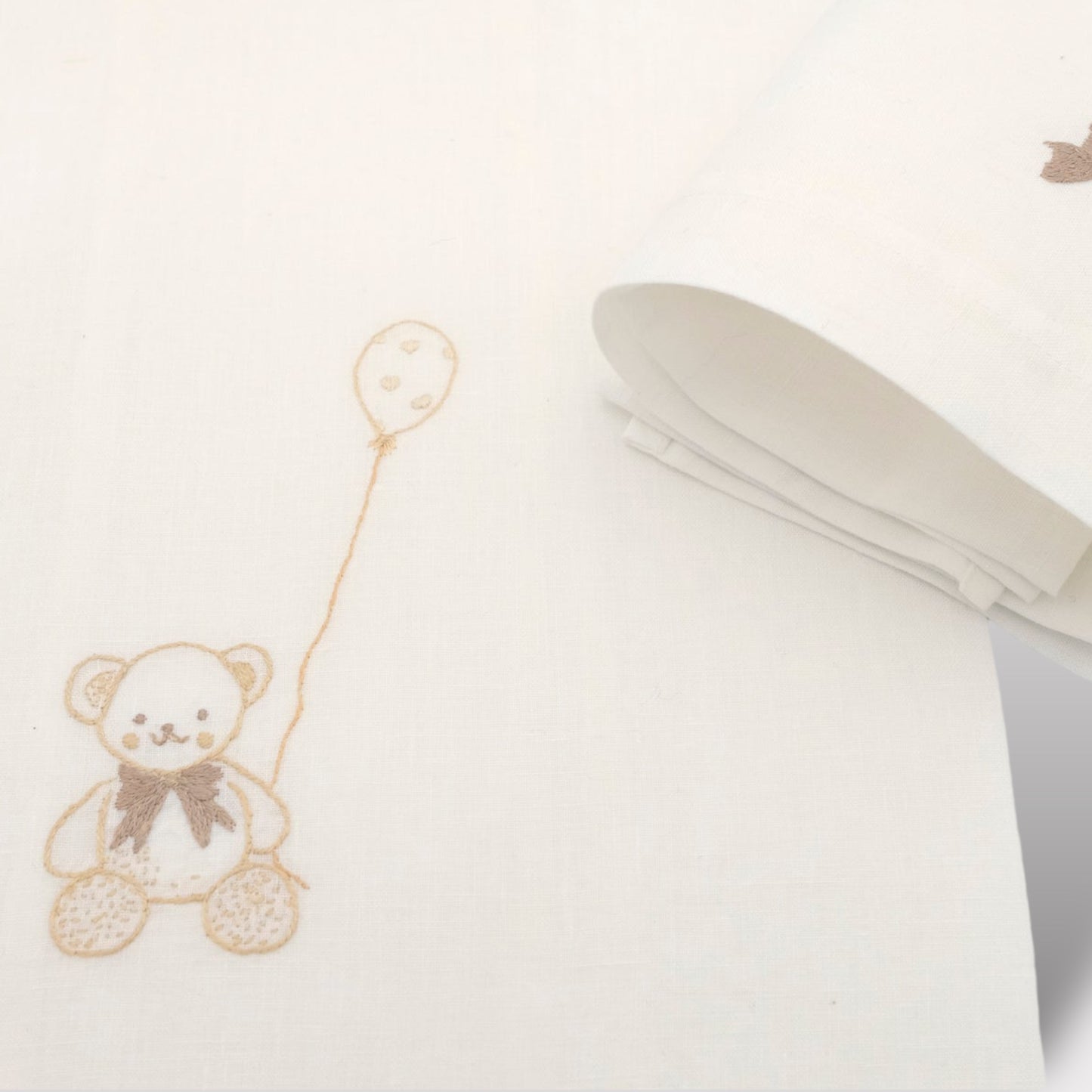 Ricamo a mano dell'orsetto sul corredino da neonato