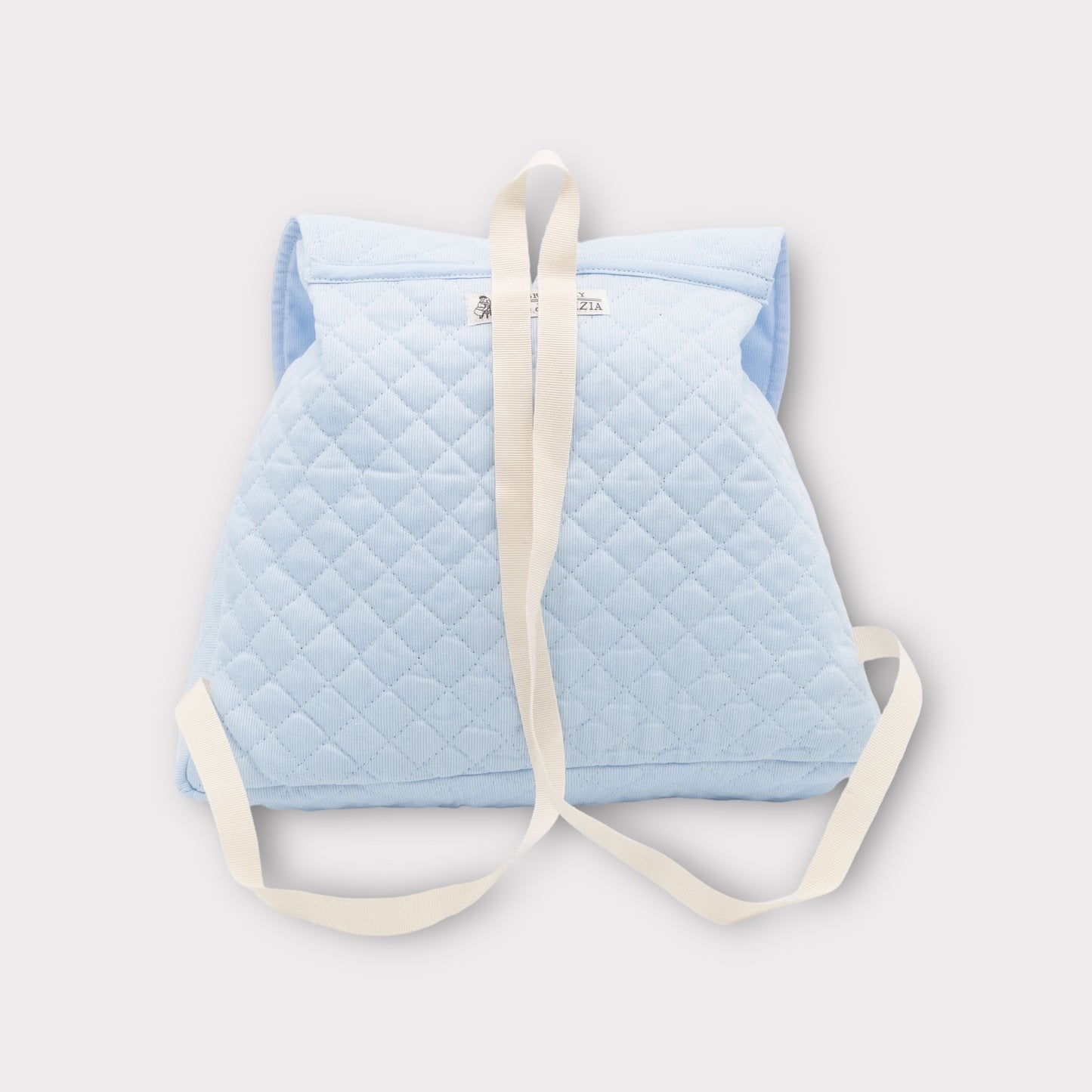 Light blue quilted backpack with teddy bear and train